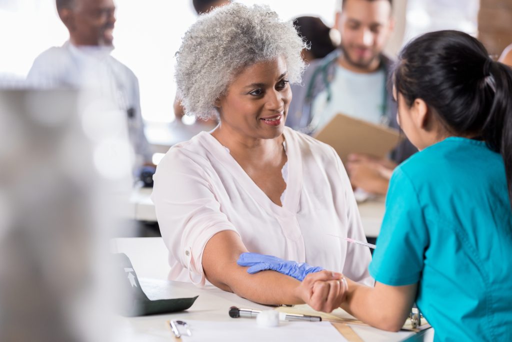 Beautiful senior African American female patient prepares to receive a flu vaccine at a free medical clinic.