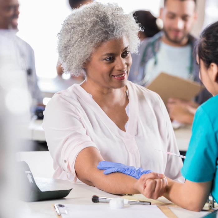 Beautiful senior African American female patient prepares to receive a flu vaccine at a free medical clinic.